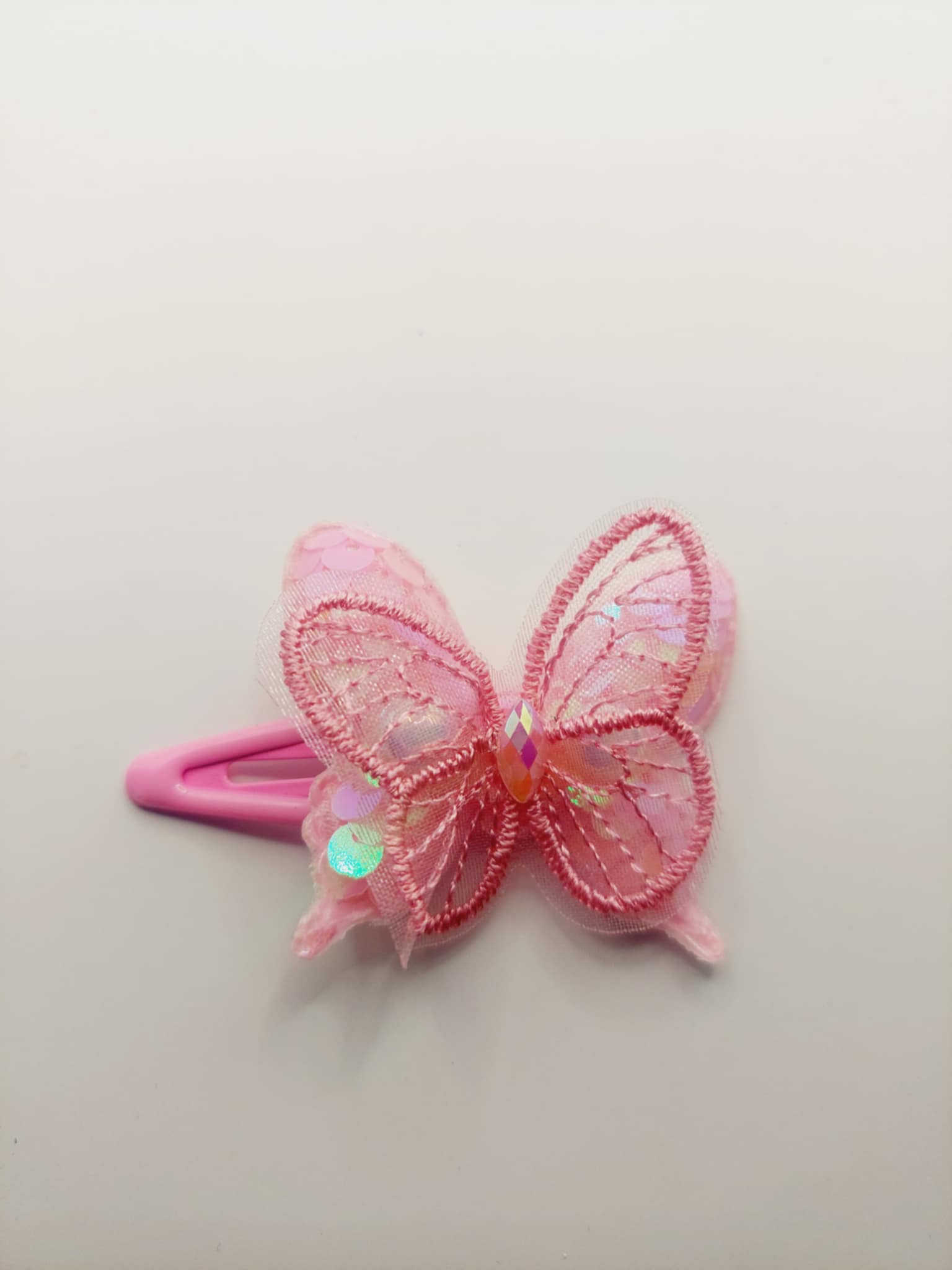 Haarclip met een rubber coating met een roze vlinder met glitter en pailletjes